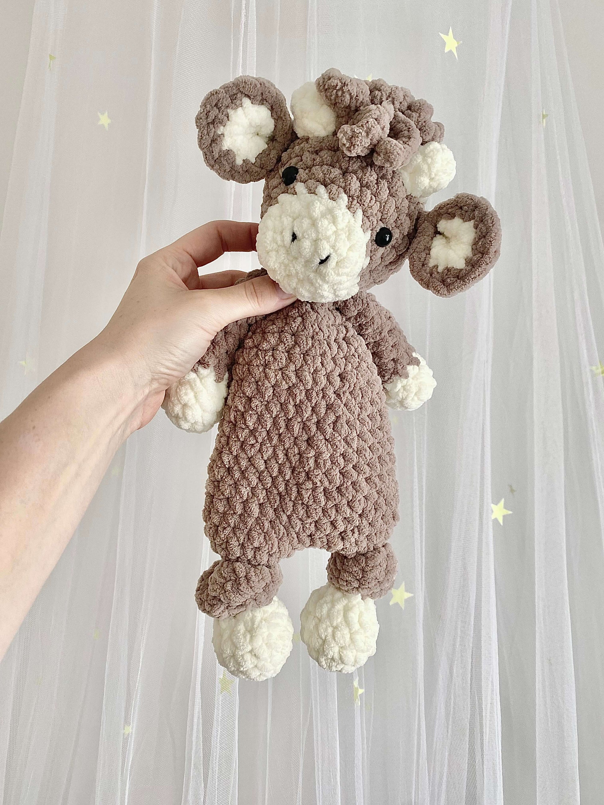 A soft and huggable Highland Cow plushie made with thick chenille yarn. This 2-in-1 crochet pattern includes a cuddly toy and snuggler version, featuring realistic cow details such as fluffy fur and small curved horns.